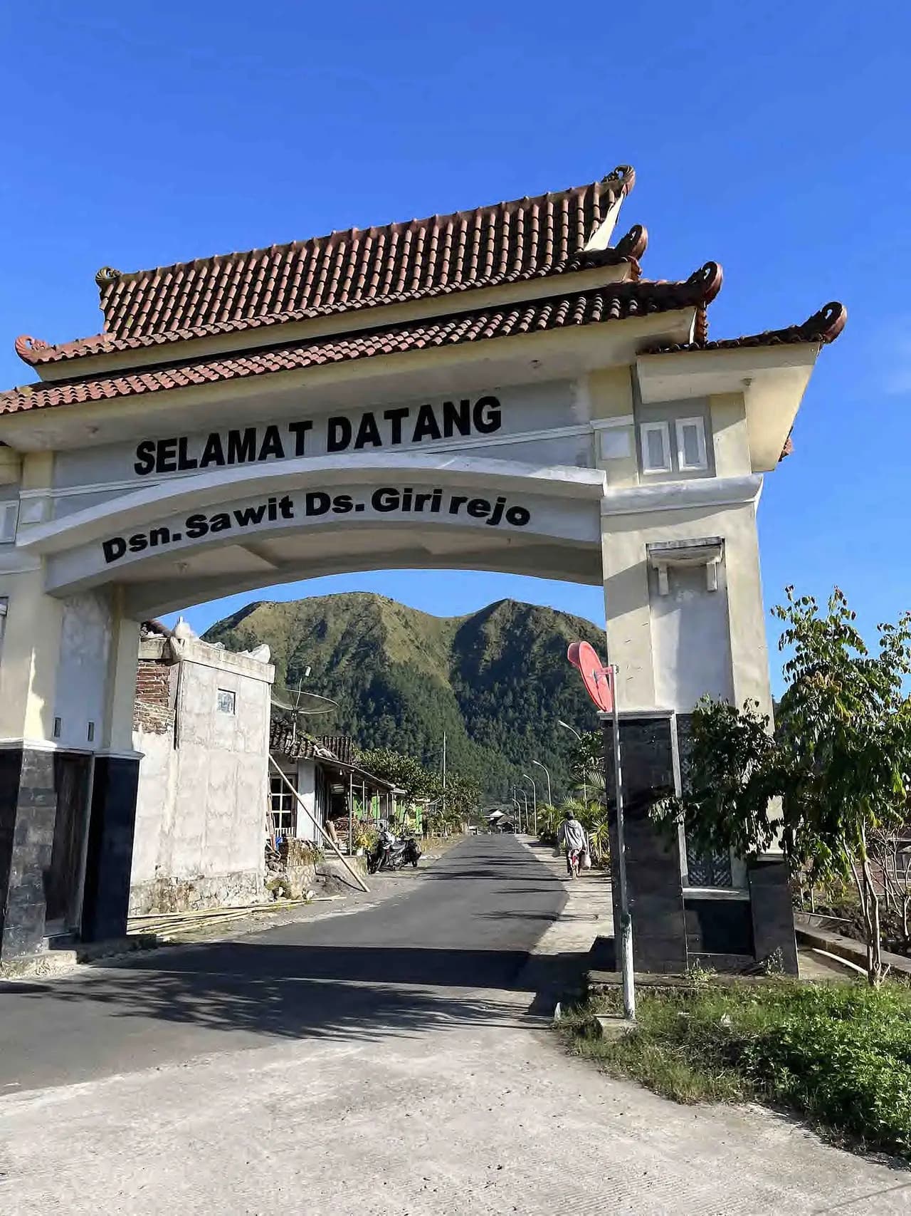 Gapura Selamat Datang Dusun Sawit, Desa Girirejo, dengan bukit hijau di latar belakang