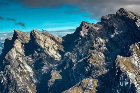Tebing batu kapur bergerigi di pegunungan kawasan Carstensz, Papua Tengah, di bawah langit biru dan awan gelap