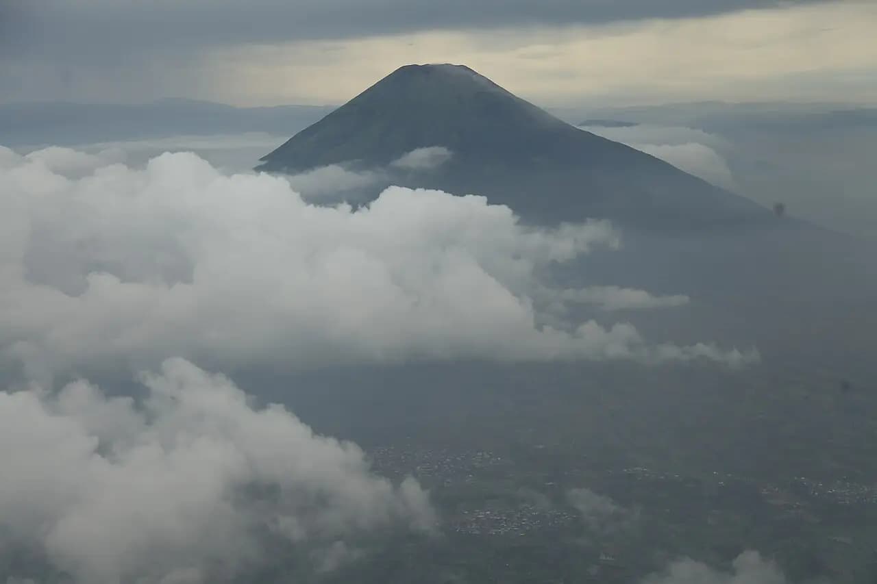 Puncak kerucut Gunung Sindoro di atas lautan awan, difoto dari puncak Gunung Sumbing