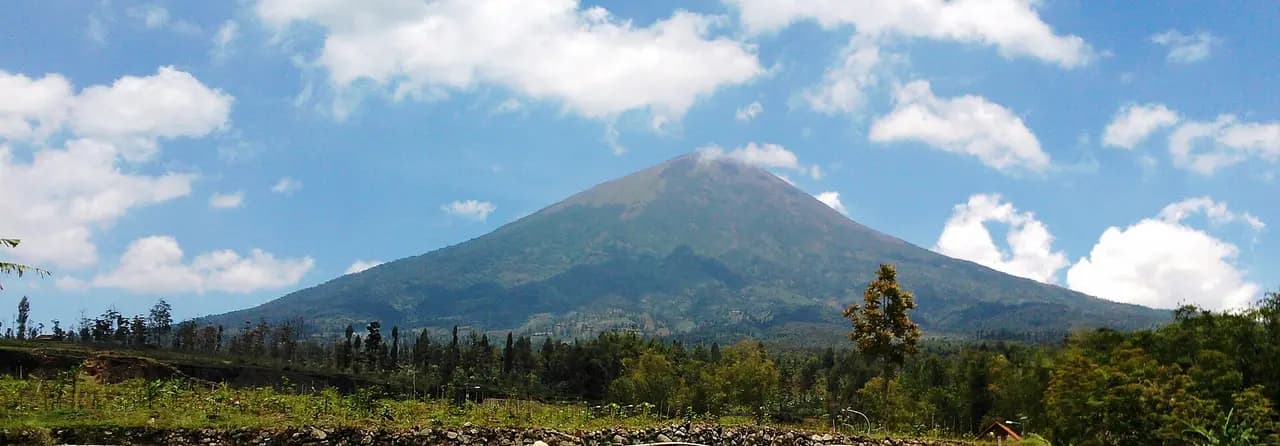Panorama Gunung Sindoro utuh di bawah langit biru, dilihat dari kawasan Situs Liyangan di lereng timur laut