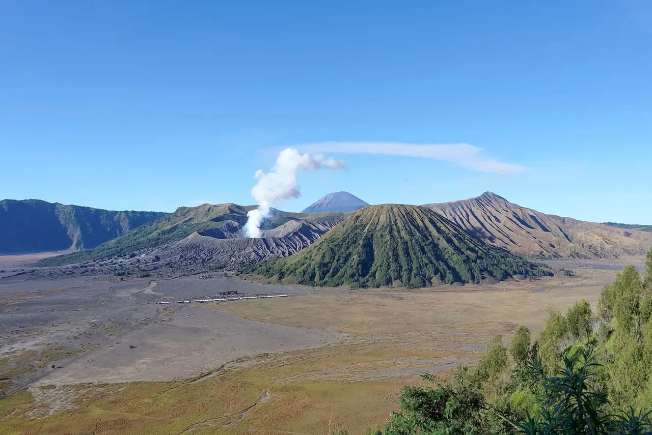 Kaldera Tengger dengan kawah Gunung Bromo yang berasap, Gunung Batok, dan Gunung Semeru di kejauhan
