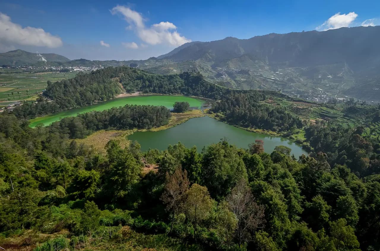 Telaga Warna yang hijau terang dan Telaga Pengilon yang lebih gelap dilihat dari ketinggian, dikelilingi hutan dan ladang