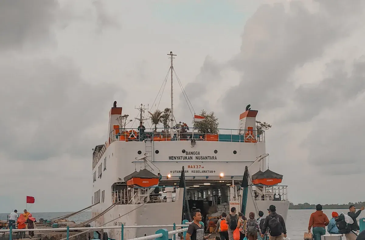 Kapal KMP Siginjai bersandar di dermaga dengan pintu rampa terbuka dan penumpang berjalan menuju kapal