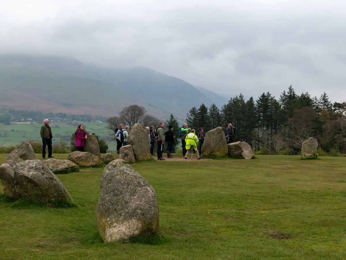 Pemandu wisata menjelaskan sejarah Lingkaran Batu Castlerigg kepada rombongan wisatawan di Cumbria, Inggris