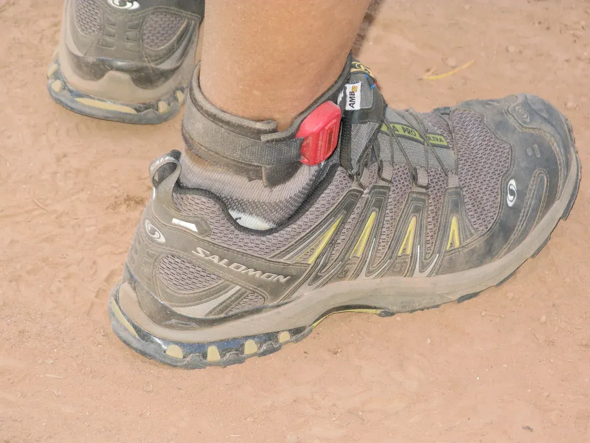 Sepatu trail running berwarna abu-abu yang dipakai di jalur tanah berdebu