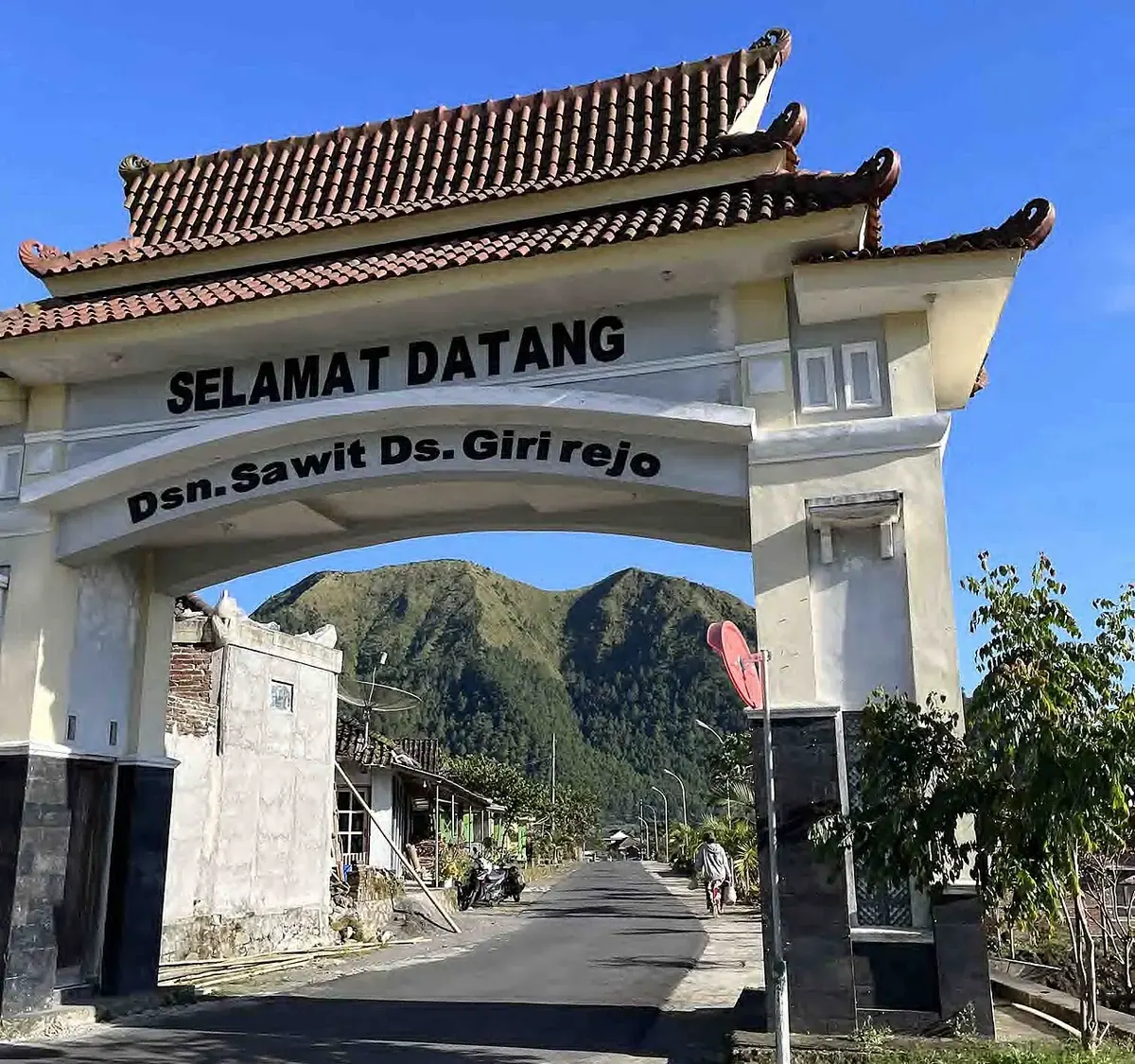 Gapura bertuliskan Selamat Datang Dsn. Sawit Ds. Girirejo dengan Gunung Andong di latar belakang